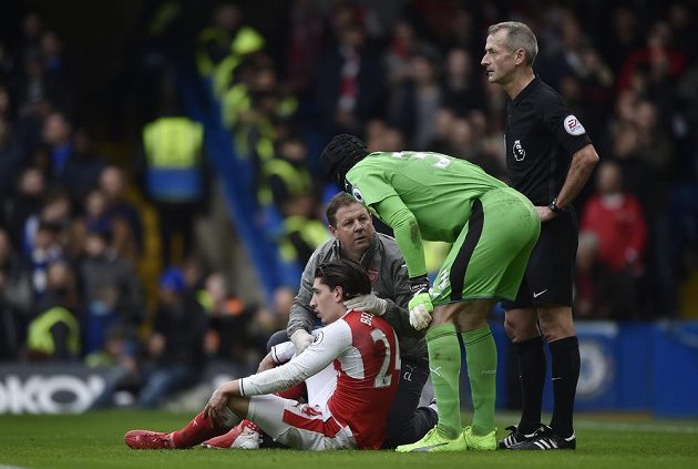 Petr Čech se sklání nad otřeseným Hectorem Bellerínem. Zadák Arsenalu nakonec musel po zákroku, jenž předcházel úvodnímu gólu Chelsea, střídat.