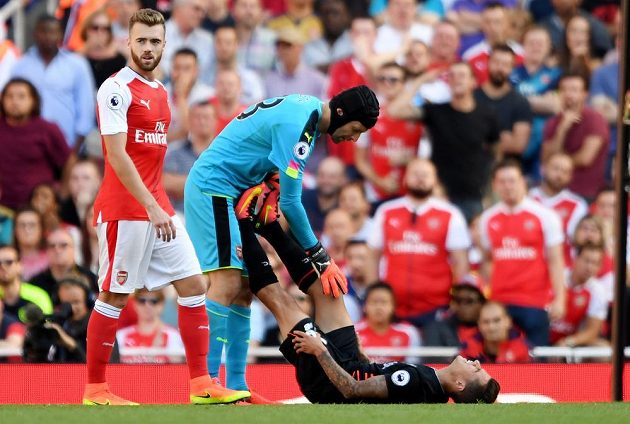 Liverpoolský Philippe Coutinho dostává pomoc od brankáře Arsenalu Petra Čecha, kolem něhož prochází spoluhráč Calum Chambers.