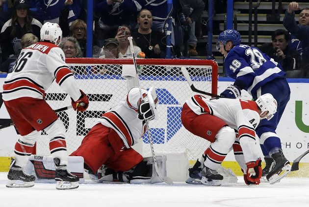Český hokejový útočník Tampy Bay Lightning Ondřej Palát (18) sleduje, zda se brankáři Caroliny Petru Mrázkovi podaří zastavit puk dřív, než skončí v brance. Nakonec mohl Palát slavit gól.