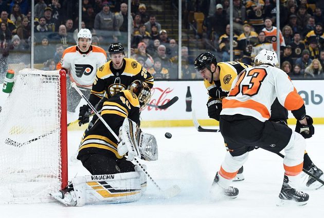 Brankář Bostonu Tuukka Rask (40) chytá puk v utkání NHL. Před ním sleduje situaci obránce Bruins Zdeno Chára (33), poblíž branky je i útočník Philadelphie Flyers Jakub Voráček (93).