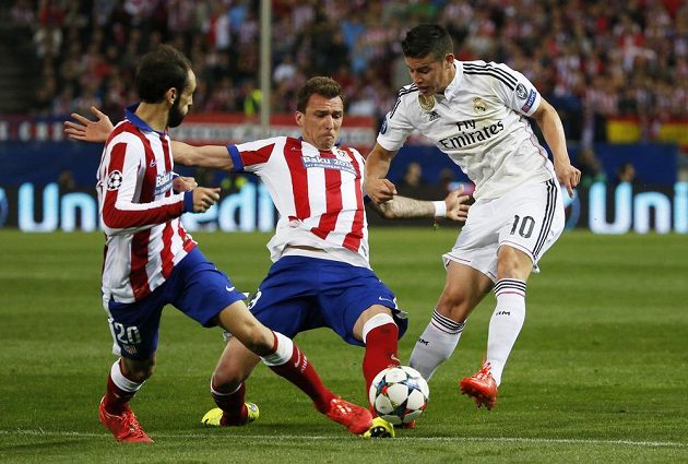 James Rodríguez z Realu se snaží prostřelit míč přes dvojici hráčů Atlétika Madrid - brání Juanfran a Mario Mandžukič (uprostřed).