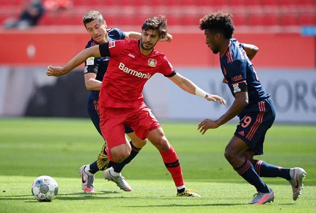 Alaksandar Dragovič z Bayeru Leverkusen v akci, atakuje jej zezadu Robert Lewandowski a z pravé strany dobíhá Kingsley Coman z Bayernu.