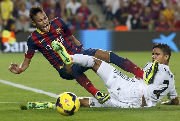 Útočník Barcelony Neymar v tvrdém souboji s Raphaelem Varanemk z Realu Madrid.