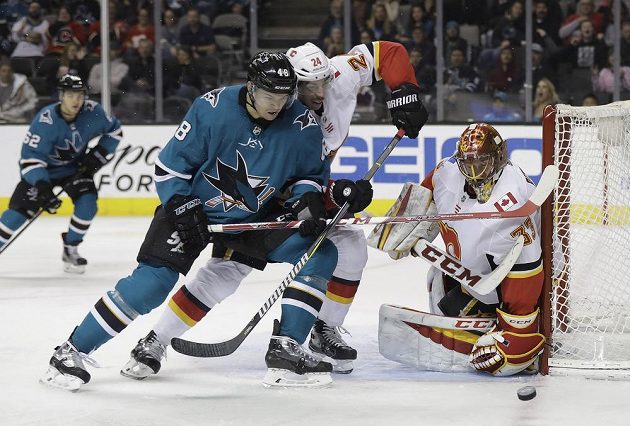 Útočník San Jose Tomáš Hertl se snaží v utkání NHL prosadit před brankou Calgary Flames. Vše sleduje český gólman Plamenů David Rittich.