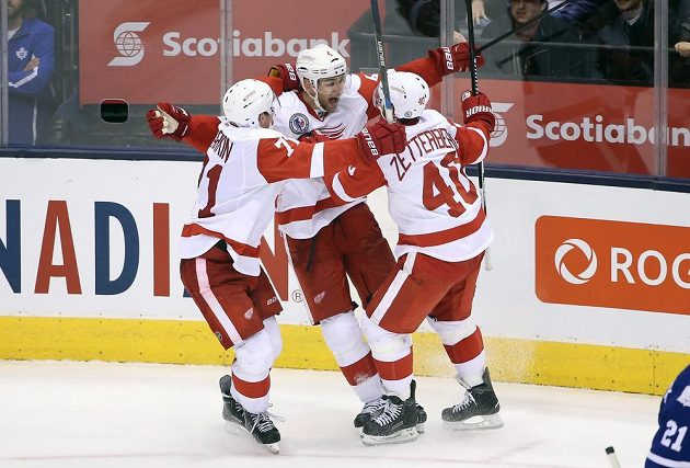 Dylan Larkin (71) a Henrik Zetterberg (40) objímají Jakuba Kindla (4) po jeho vítězné trefě v duelu proti Torontu Maple Leafs.