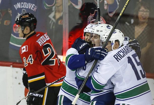 Útočník Vancouveru Mike Santorelli (druhý zprava) slaví se spoluhráči vítězný gól do sítě Calgary. Vlevo zklamaný forvard Flames Jiří Hudler.