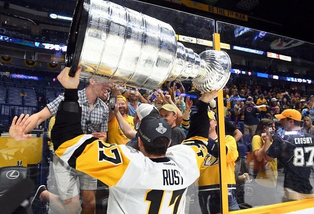 Pravé křídlo hokejového Pittsburghu Penguins Bryan Rust slaví se Stanley Cupem nad hlavou na ledě Nashvillu Predators.