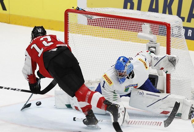Rakouský hokejista Michael Raffl dává gól do sítě italského gólmana Andrease Bernarda.