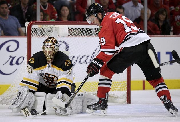 Brankář Bostonu Tuukka Rask kryje puk před Jonathanem Toewsem z Chicaga během druhé třetiny úvodního finále Stanley Cupu.