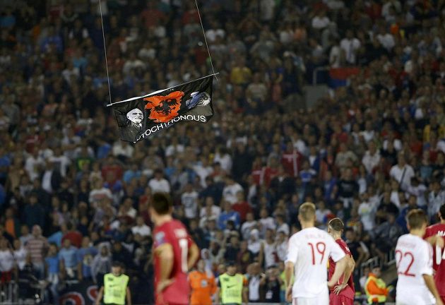 Fotbalisté Srbska a Albánie se dívají na vlajku, která se vznáší nad trávníkem.