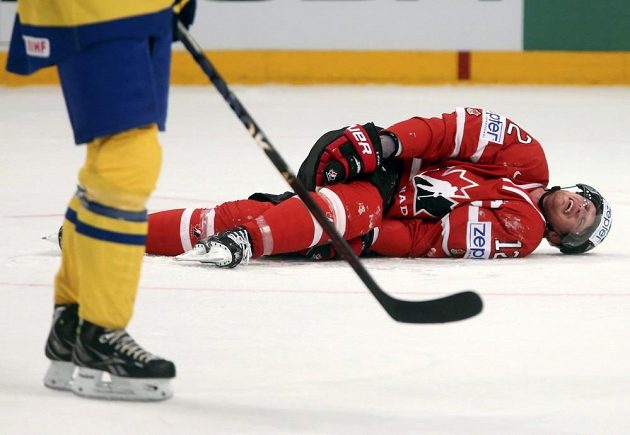 Kapitán kanadské hokejové reprezentace Eric Staal (vpravo) se na ledě svíjí v bolestech po zákroku švédského obránce Edlera.