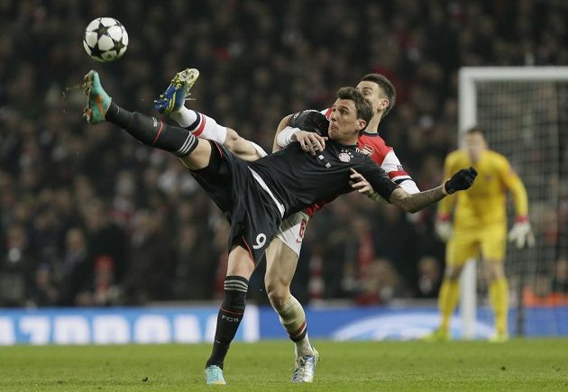 Mario Mandžukič (vlevo) z Bayernu v akrobatickém souboji s Laurentem Koscielnym z Arsenalu.