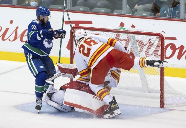 Hokejista Calgary Flames Michael Stone (26) tvrdě narazil do svého spoluhráče Daniela Vladaře v brance Plamenů v přípravném utkání s Vancouverem Canucks.