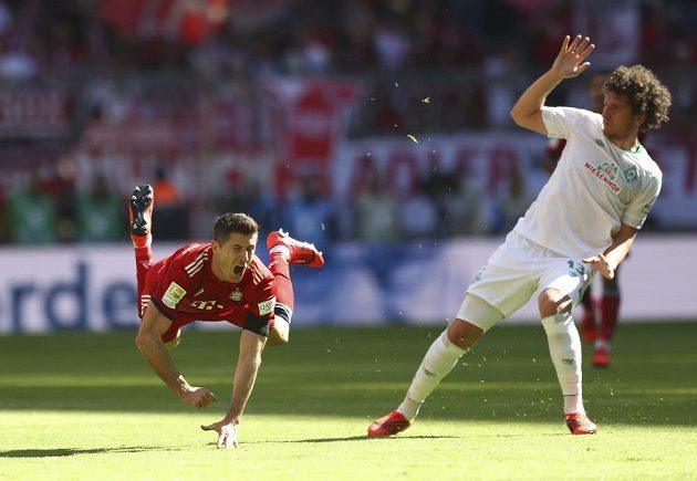 Útočník Bayernu Robert Lewandowski letí vzduchem po faulu obránce Miloše Veljkoviče z Werderu Brémy. Veljkovič pak zápas po červené kartě nedohrál.