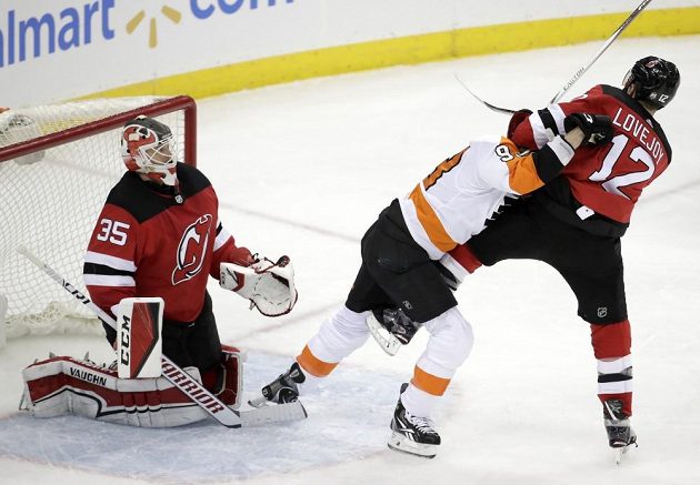 Jakub Voráček (v bílém) z Philadelphie v ostrém souboji s obráncem New Jersey Royem Lovejoyem, v brance New Jersey přihlíží Corey Schneider.
