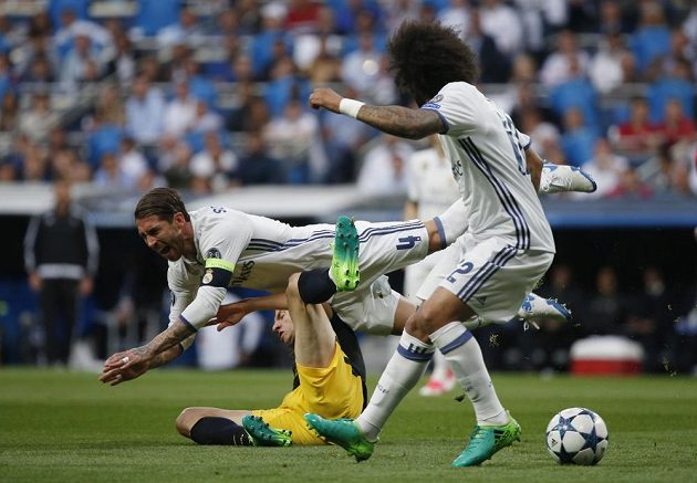 Kapitán Realu Madrid Sergio Ramos padá po souboji s Felipem Luisem z Atlétika v úvodním semifinále Ligy mistrů. Všemu přihlíží obránce Realu Marcelo.