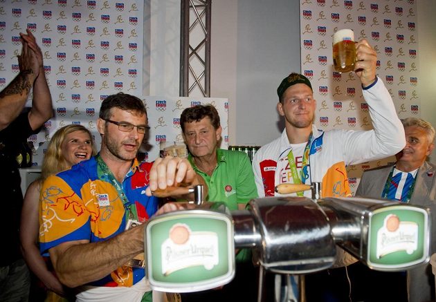 Lukáš Krpálek si na oslavu získané zlaté olympijské medaile dopřál pivo. Vlevo v popředí ho čepuje trenér Petr Lacina, vlevo v pozadí přihlíží ministryně školství Kateřina Valachová.