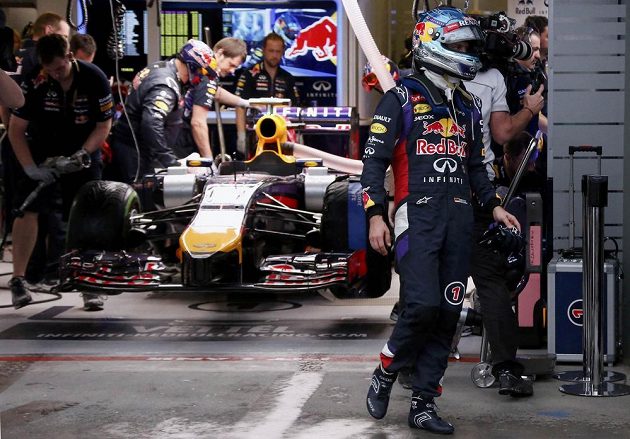 Úřadující šampión Sebastian Vettel (vpravo) zklamaně opouští garáž svého týmu Red Bull.