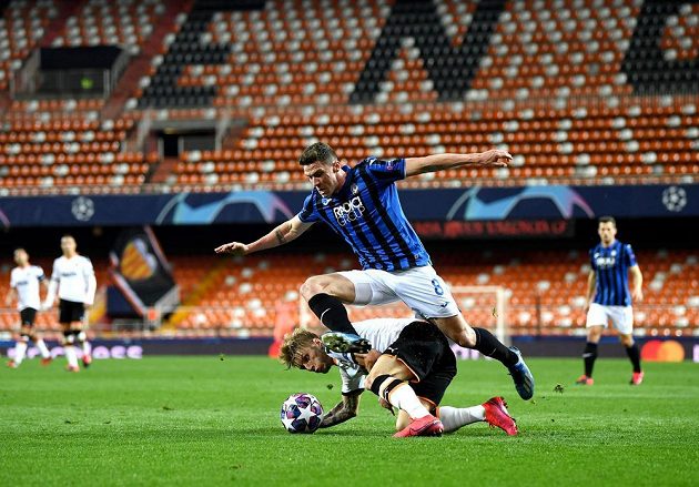Před práznými tribunami bojují o míč Daniel Wass (vlevo) z Valencie a Robin Gosens z Atalanty Bergamo.