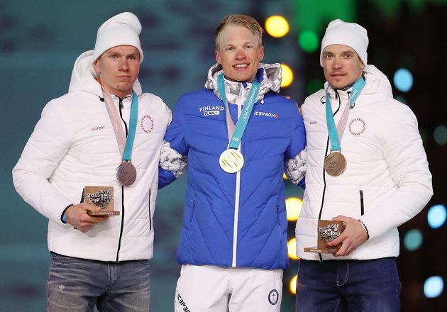 Závěrečné medailové vyhlášení závodu mužů v běhu na lyžích 50 km klasicky proběhl v rámci závěrečného ceremoniálu. Zleva stříbrný Alexander Bolšunov z týmu OSR, vítězný Iivo Niskanen z Finska a třetí Andrej Larkov z týmu OSR.