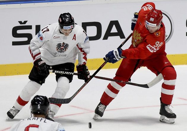 Rakouský hokejista Manuel Ganahl bojuje o puk s Michailem Sergačovem z Ruska v utkání mistrovství světa.