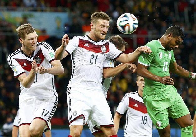 Němečtí obránci Per Mertesacker (vlevo) a Shkodran Mustafi (druhý zleva) odvrací míč před dotírajícím Arbím Hilálem Súdáním z Alžírska.