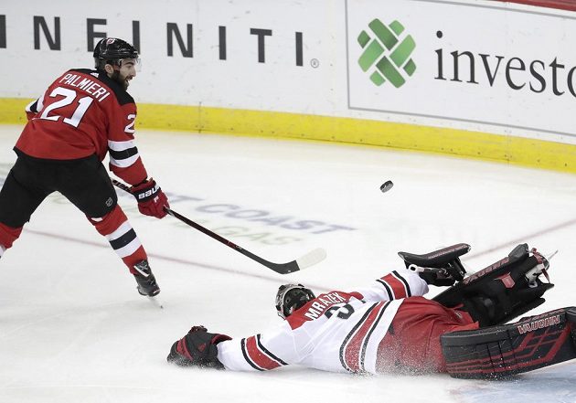 Kyle Palmieri (21) z New Jersey Devils se snaží překonat gólmana Caroliny Petra Mrázka (34) v utkání NHL.