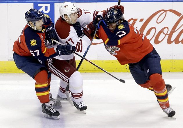 Radim Vrbata (17) z Phoenixu se snaží přejít přes dvojici bránících hokejistů Floridy Vincenta Trochecka (67) a Toma Gilberta (77).