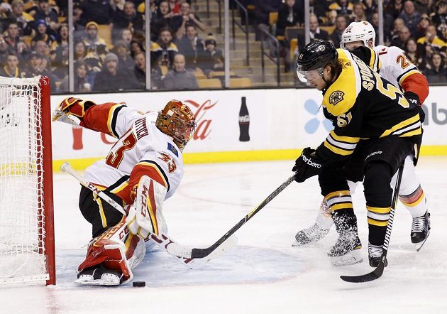 Brankář Calgary Flames David Rittich likviduje šance bostonského Ryana Spoonera v utkání NHL.