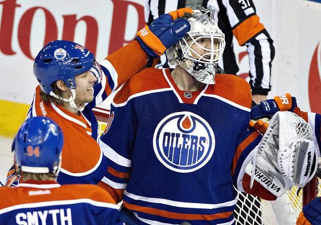 Hokejisté Edmontonu Ryan Smyth (číslo 94) a Philip Larsen (uprostřed) gratulují Benu Scrivensovi k zákroku v utkání proti San Jose.