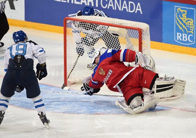 Fin Kasperi Kapanen zpoza branky překonává ruského gólmana Alexandara Georgijeva ve finále MS 20. Před brankou Aleksi Saarela.