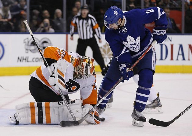 Brankář Philadelphie Michal Neuvirth se snaží zkrotit puk před dotírajícím útočníkem Toronta Zachem Hymanem.