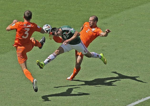 Mexičan Héctor Herrera v osmifinálovém duelu na MS zkouší prorazit nizozemským dvojblokem, který tvoří Stefan de Vrij (vlevo) a Ron Vlaar.