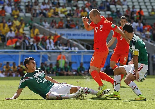 Nešťastný střet Héctora Morena s Arjenem Robbenem v závěru první půle osmifinálového duelu na MS. Vpravo je mexický kapitán Rafael Márquez.