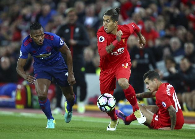 Záložník Liverpoolu Roberto Firmino se rozhlíží komu nahraje, obránce Manchesteru United Eric Bailly nestíhá.