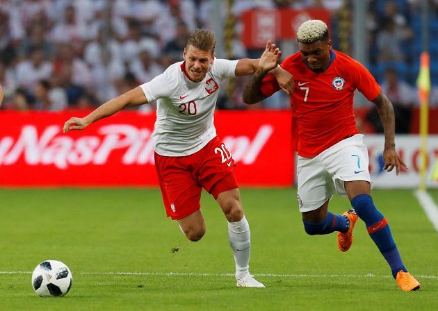 Polský fotbalista Lukasz Piszczek v akci během přípravného utkání s Chile. Souboj svádí s Chilanem Juniorem Fernandesem.