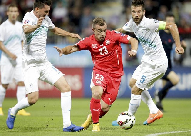 Švýcar Xerdan Shaqiri (uprostřed) si vede míč mezi Bostjanem Cesarem (vpravo) a Andrazem Kirmem ze Slovinska.