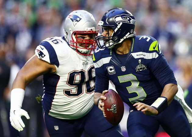 Quarterback Russell Wilson (vpravo) z týmu Seattle Seahawks se snaží uniknout Sealveru Siligovi z týmu Patriotů.