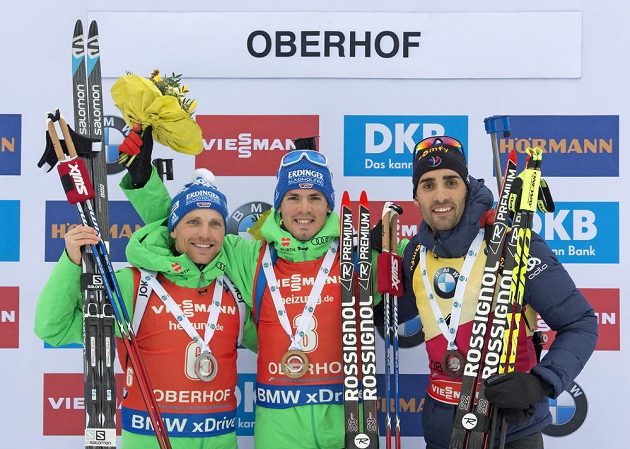 Simon Schempp oslavuje na bedně své vítězství s druhým Erikem Lesserem a třetím Martinem Fourcadem.