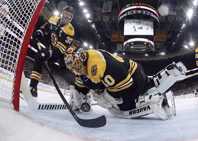 Brankář Bostonu Tuukka Rask se za asistence kapitána týmu Zdena Cháry snaží zkrotit puk v rozhodujícím sedmém finále Stenley Cupu proti St. Louis.