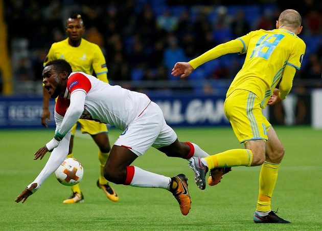 Fotbalista Slavie Michael Ngadeu-Ngadjui padá k zemi po souboji s Ivanem Majevským z Astany v utkání Evropské ligy.