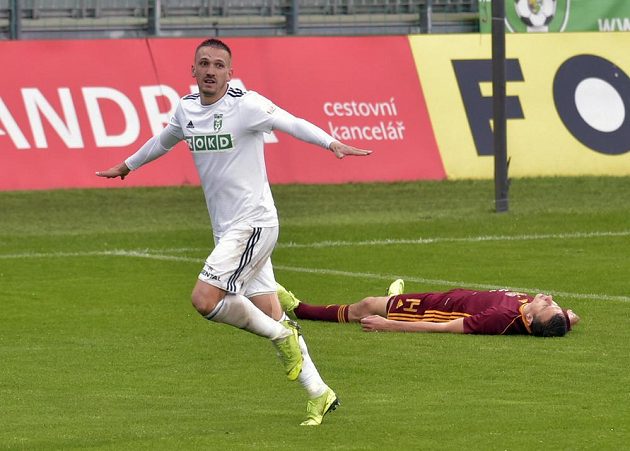 Karvinský David Guba se raduje ze vstřelené branky. Na trávníku leží Ivan Ostojič z Dukly.