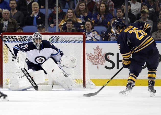 Ondřej Pavelec (31) z Winnipegu v utkání s Buffalem, ohrozit se ho snaží Matt Moulson (26.