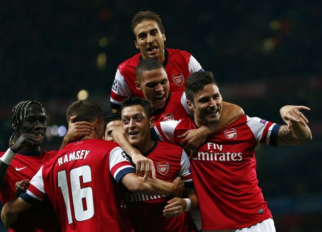 Fotbalisté Arsenalu oslavují úvodní trefu Mesuta Özila (dole uprostřed) v utkání Ligy mistrů proti Neapoli.