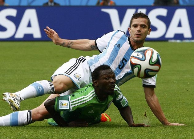 Argentinec Fernando Gago (nahoře) v souboji s Juwonem Oshaniwou z Nigérie.