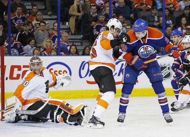 Brankář Flyers Michal Neuvirth se otáčí za střelou Leona Draisaitla (29) z Edmontonu.