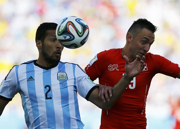 Argentinský obránce Ezequiel Garay (vlevo) v souboji se švýcarským útočníkem Josipem Drmičem.