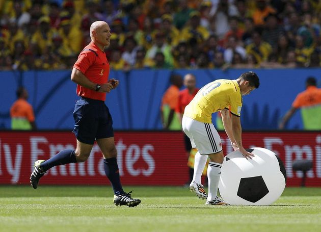 Rozhodčí Howard Webb a Kolumbijec James Rodriguez s nezvyklou překážkou ve hře.
