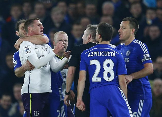 Branislav Ivanovič z Chelsea (vlevo) drží pod krkem Jamese McCarthyho z Evertonu. Všemu přihlíží rozhodčí Jonathan Moss.