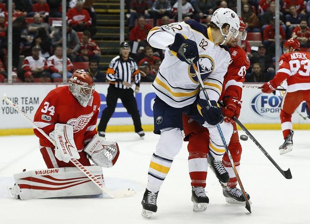 Český gólman Detroitu Petr Mrázek v brance Rudých křídel v duelu NHL s Buffalem Sabres. Před brankou mu cloní Marcus Foligno z Buffala, hlídá jej Xavier Ouellet. Detroit zápas prohrál 1:2.